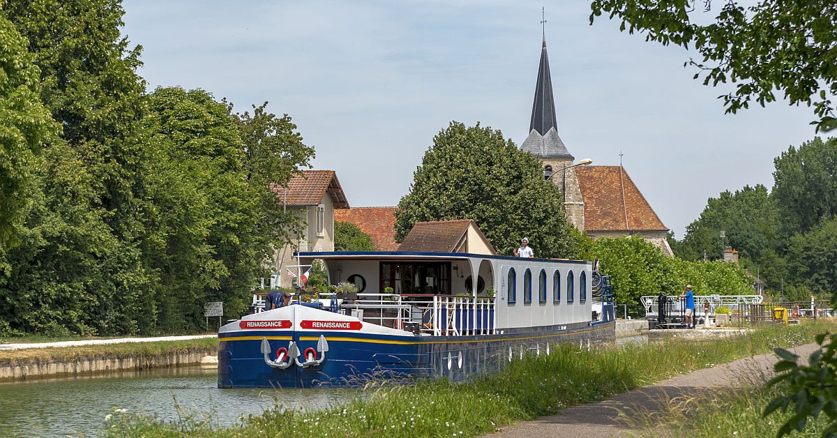 A Renaissance-branded river cruise boat with distinctive blue hull and white upper cabin navigates