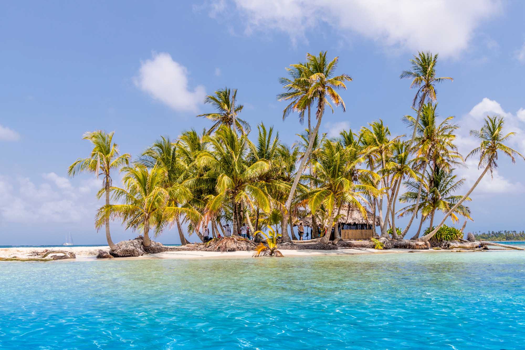 A pristine tropical island dotted with coconut palms and traditional structures, surrounded