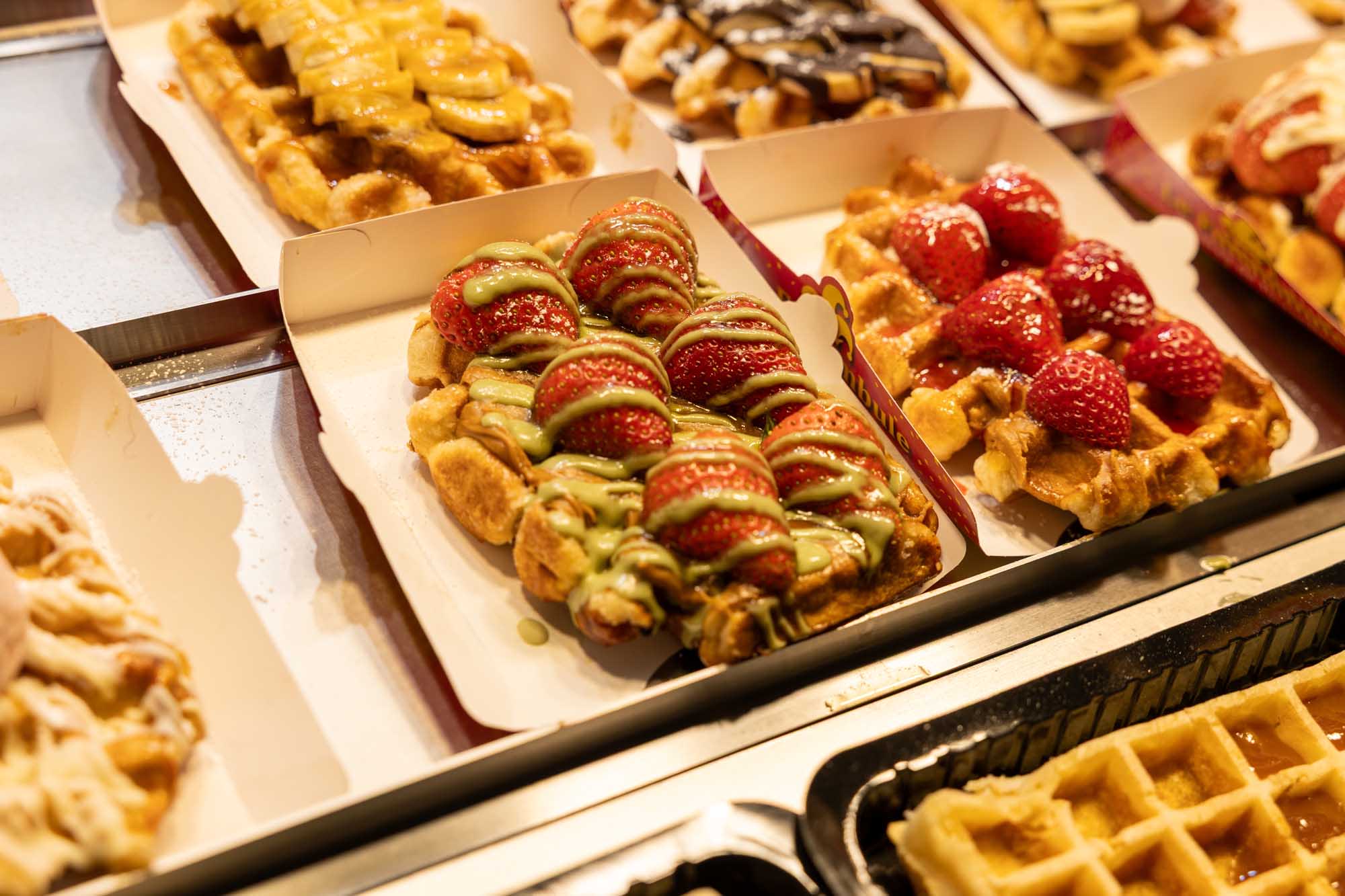 A delightful display of traditional Belgian waffles served in cardboard takeaway boxes, beautifully