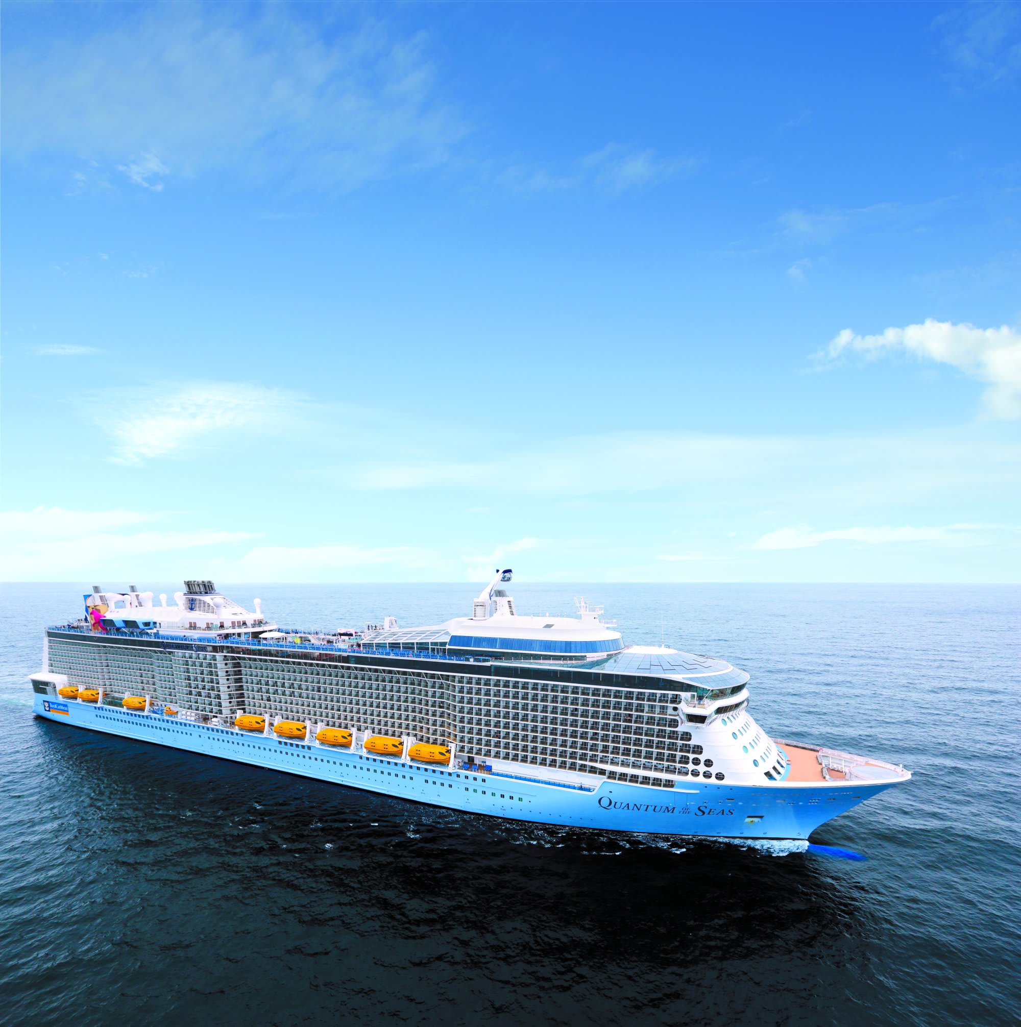 A large modern cruise ship photographed from above while sailing on open ocean waters under a clear