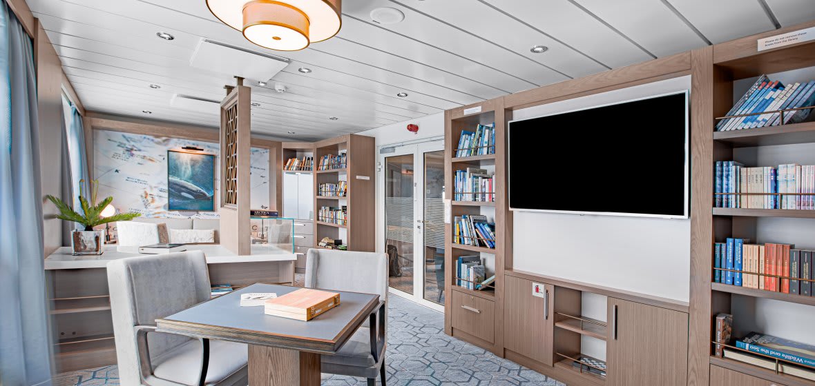Modern library and lounge area aboard an Albatross expedition cruise ship with comfortable seating and bookshelves.