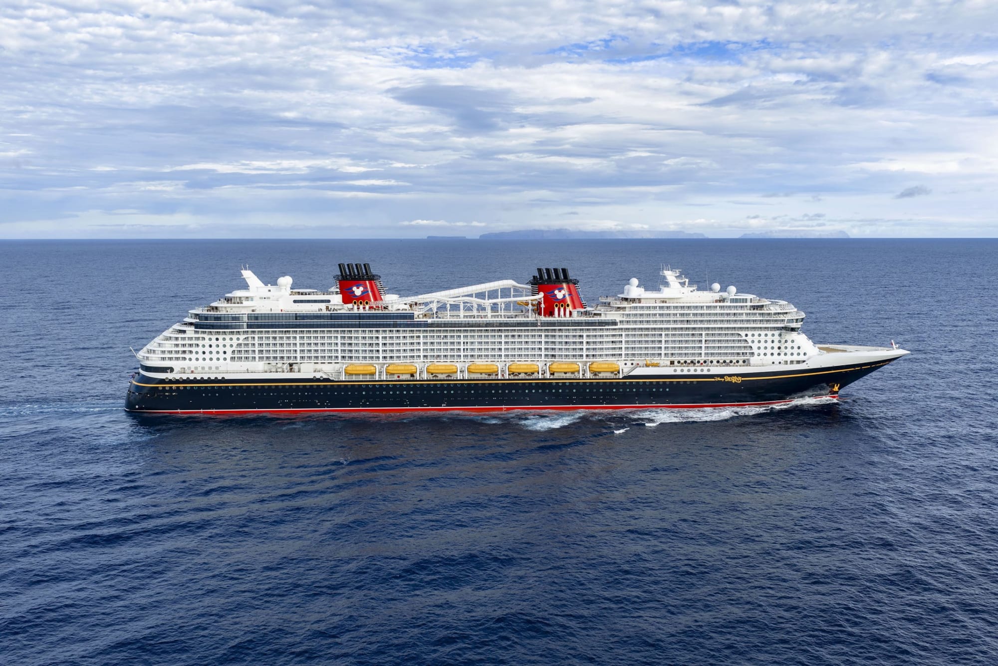 A massive modern cruise ship with white superstructure and black hull featuring distinctive red