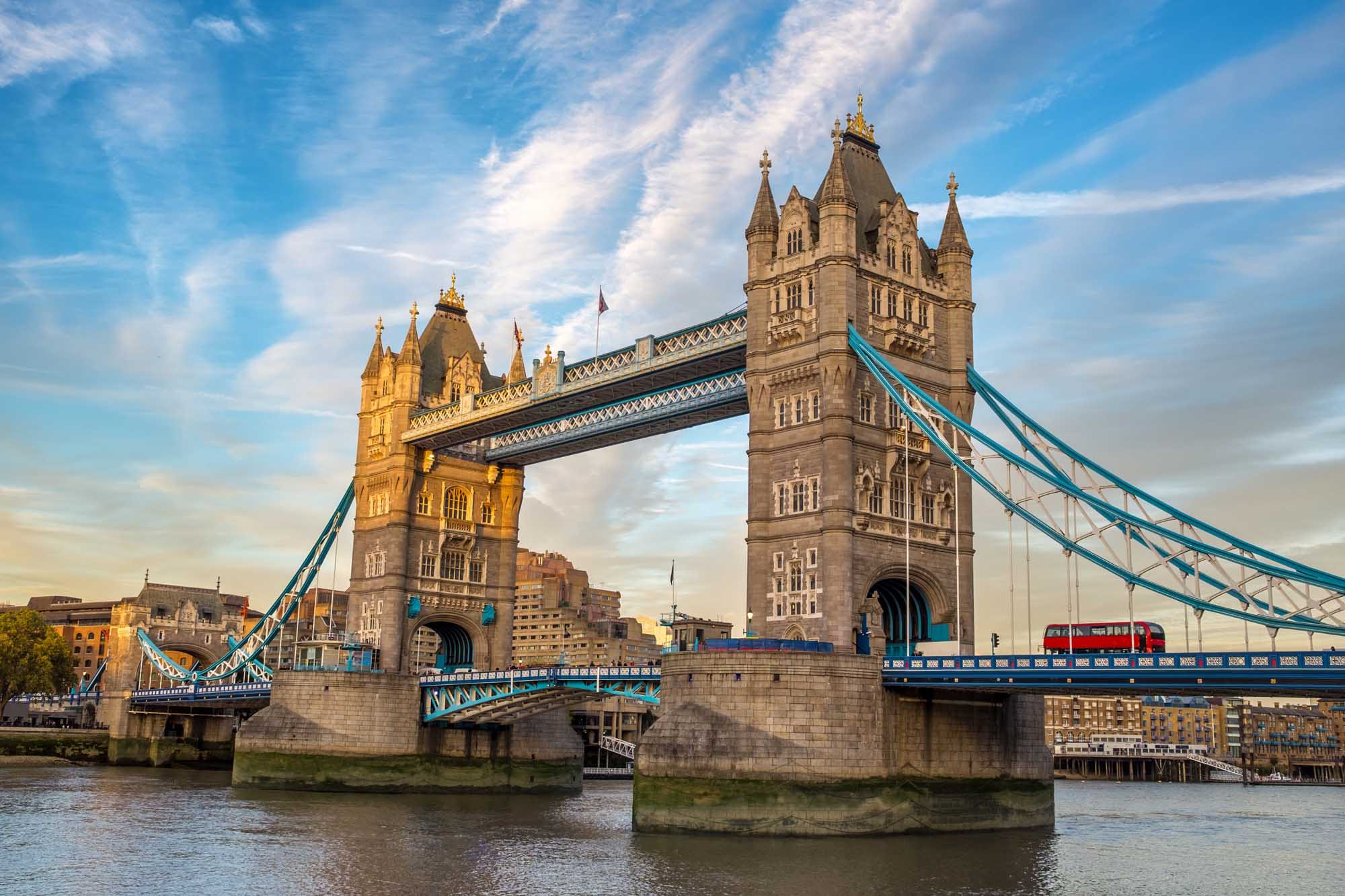 An iconic view of Tower Bridge spanning the River Thames in London, illuminated by golden evening