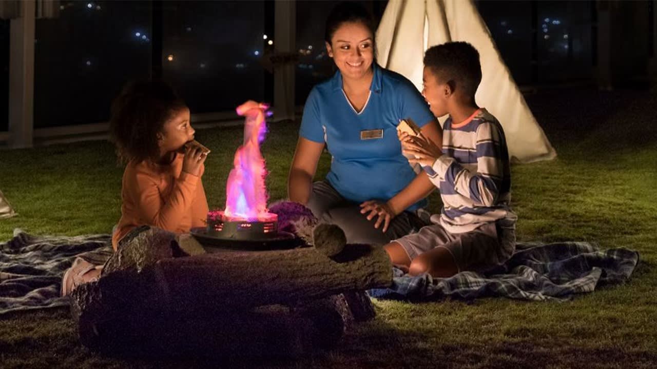A staff member from Celebrity Cruises engages with two children during an evening kids' club