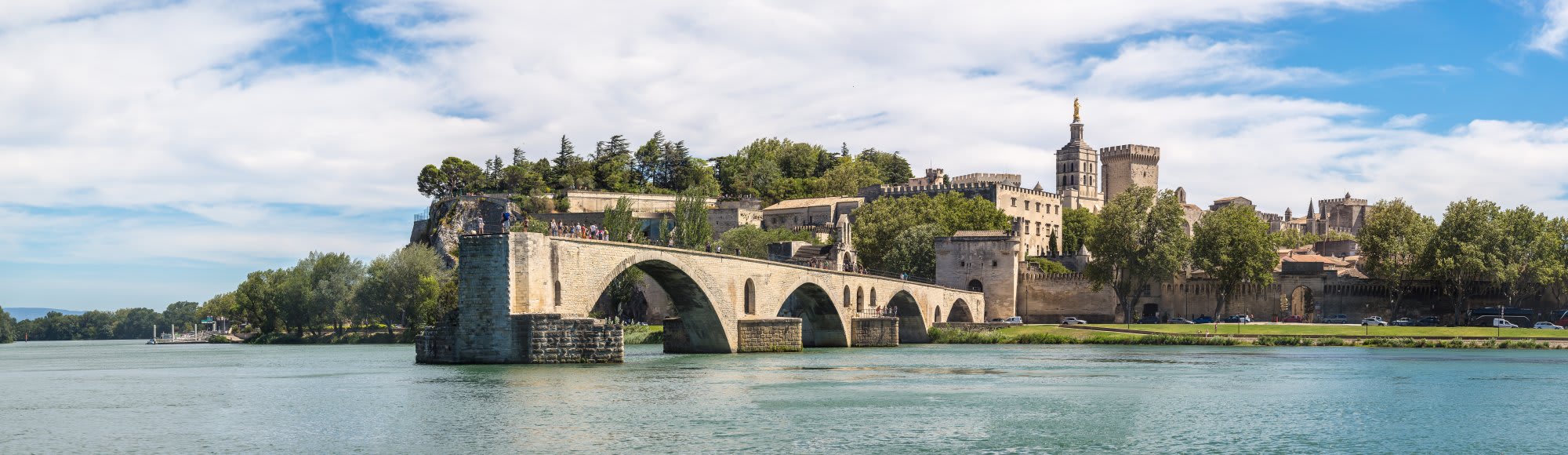 A stunning panoramic view of the historic Pont d'Avignon (Saint-Bénézet Bridge) spanning the Rhône
