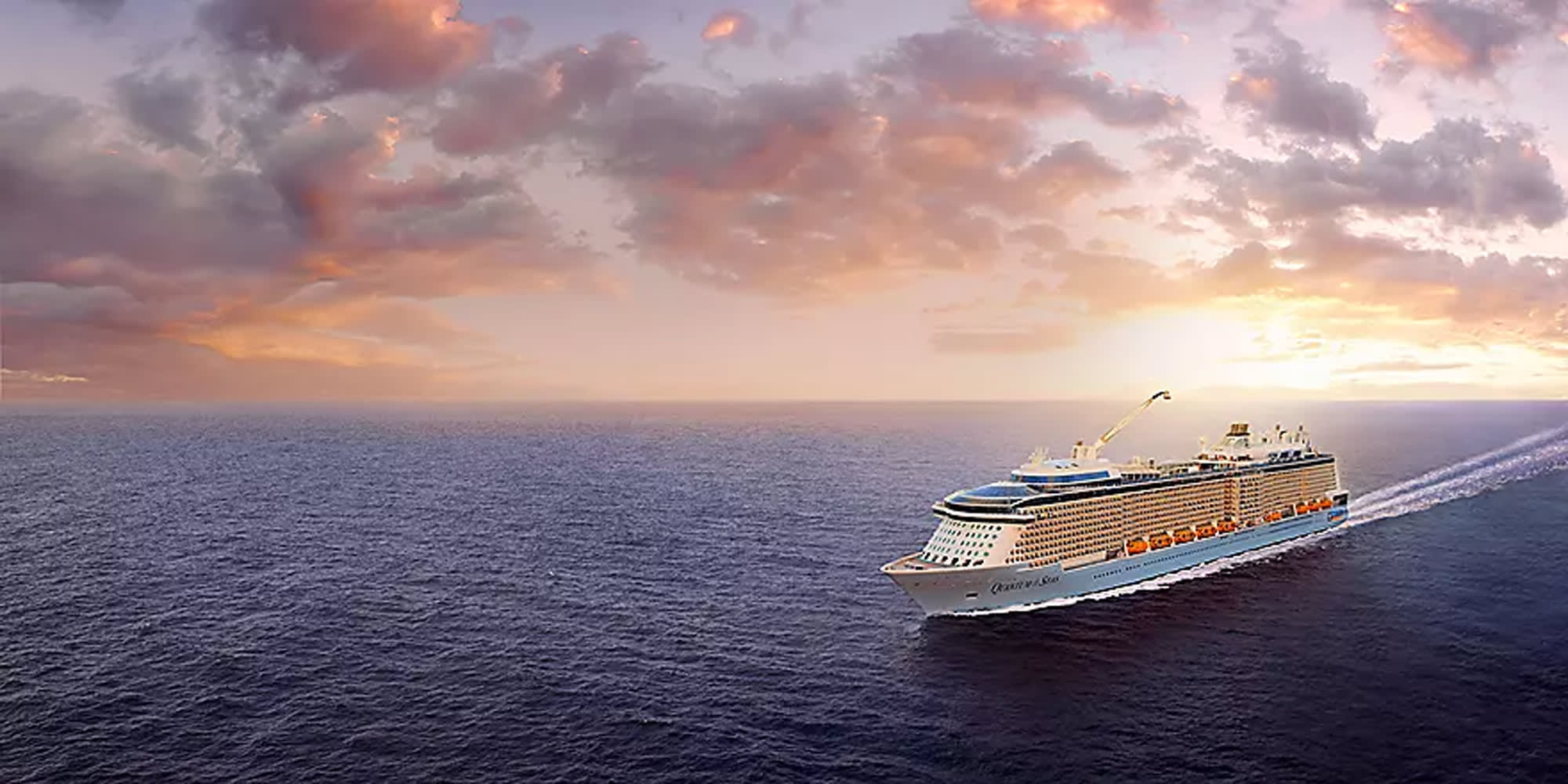 A massive modern cruise ship sails through calm blue waters during a stunning golden sunset