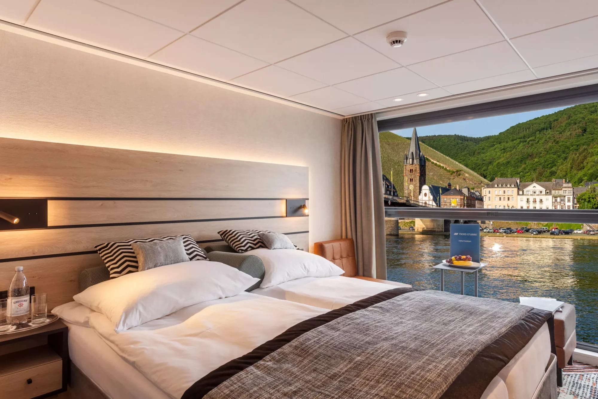 A sophisticated river cruise cabin featuring a modern bedroom with panoramic floor-to-ceiling