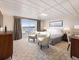 A spacious and elegantly appointed suite aboard an American Cruise Lines vessel, featuring a king
