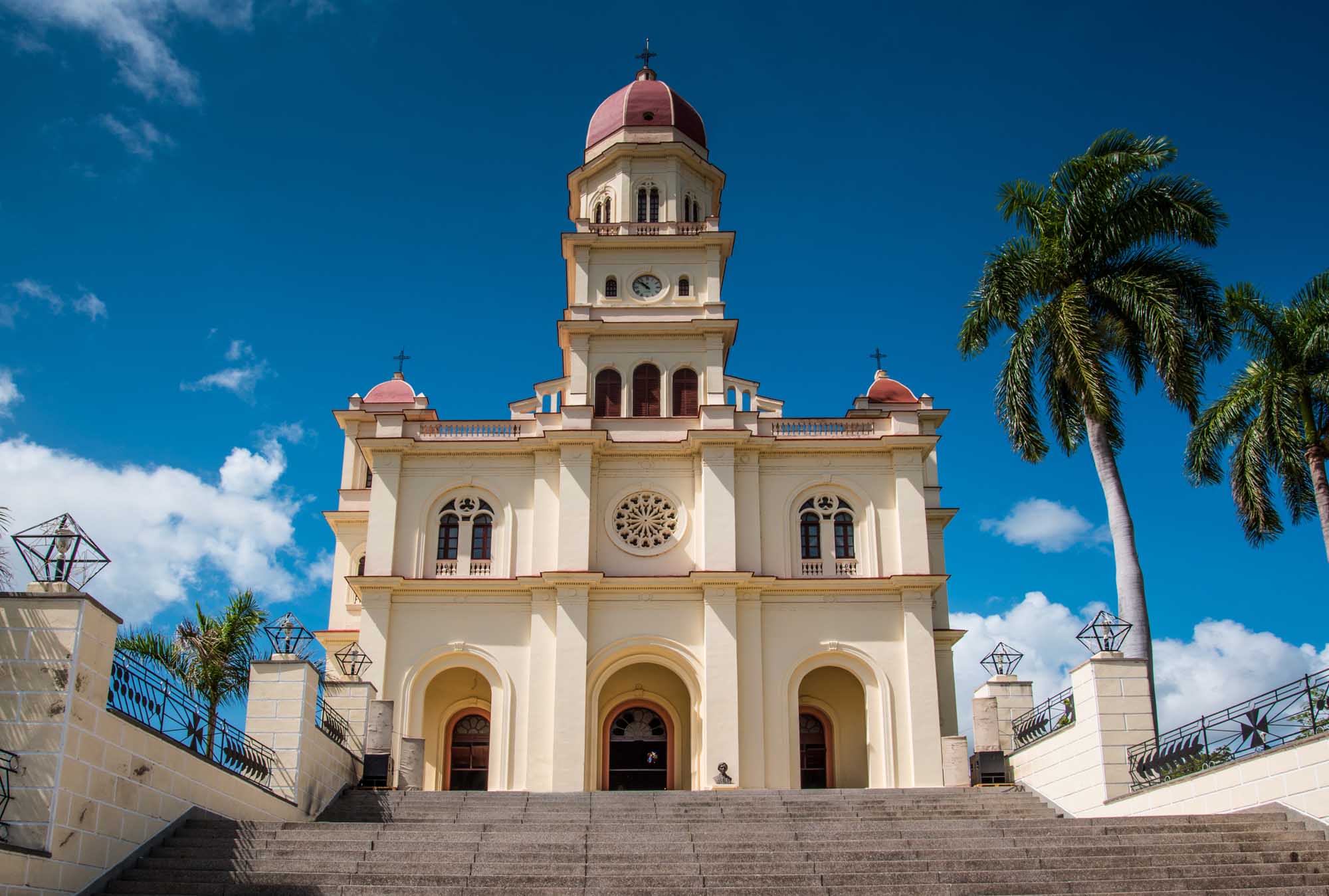 A striking neoclassical basilica with cream-colored walls, red-tiled dome, and ornate architectural