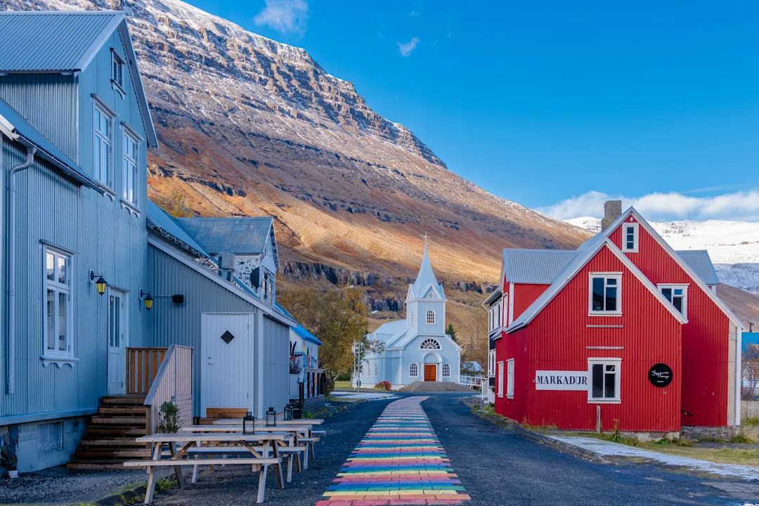 A picturesque Icelandic village nestled beneath dramatic mountains, featuring traditional