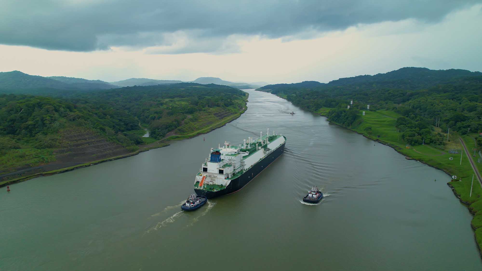 A large cargo vessel is escorted by tugboats through the Panama Canal, one of the world's most