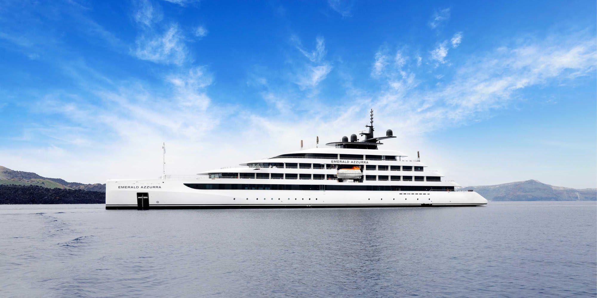 The Emerald Azzurra, a sleek white luxury expedition yacht, anchors in clear blue waters