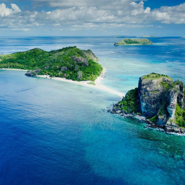 A stunning aerial view of pristine tropical islands featuring white sand beaches, lush green