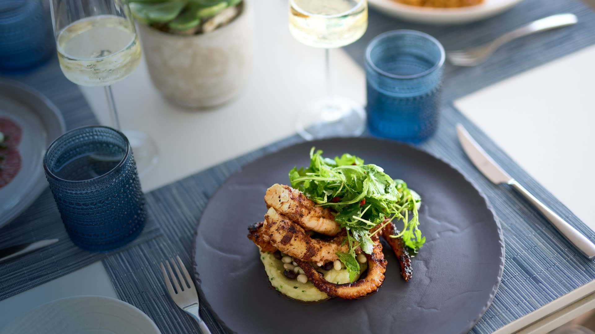 An elegantly plated seafood dish featuring seared scallops on a bed of cauliflower purée, topped