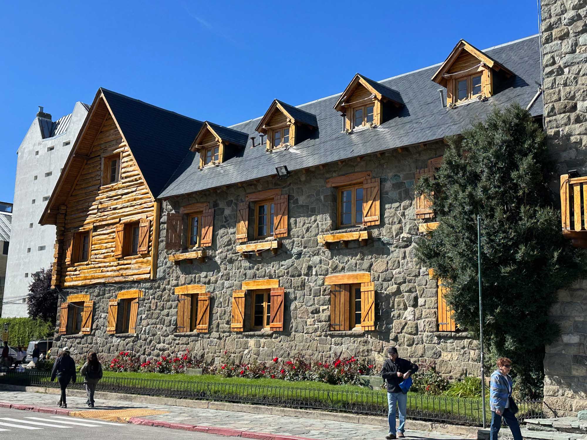 A striking heritage stone building featuring a mansard roof with dormer windows, golden wooden