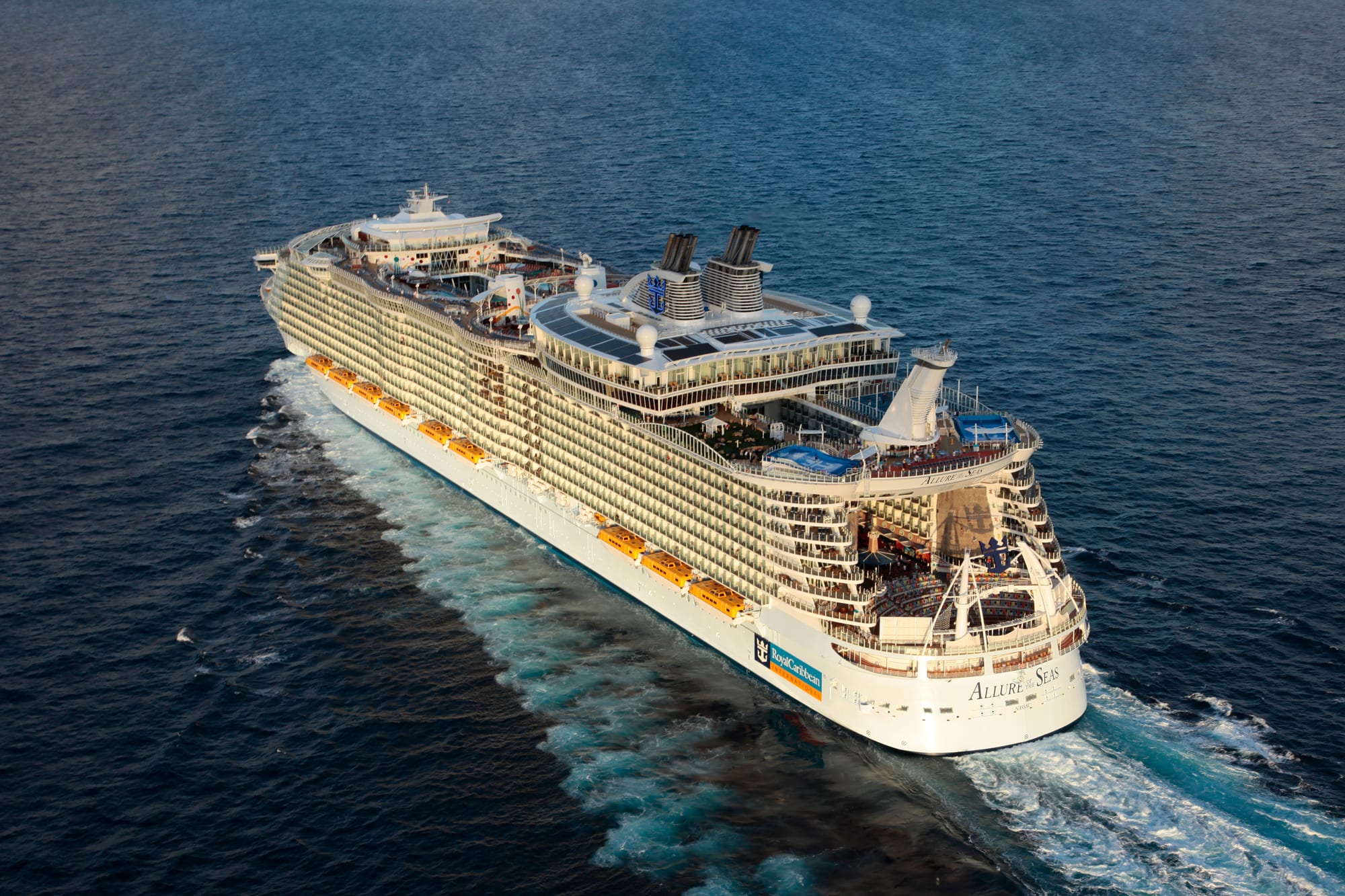 An aerial view of the Allure of the Seas, a massive modern cruise ship, positioned in shallow