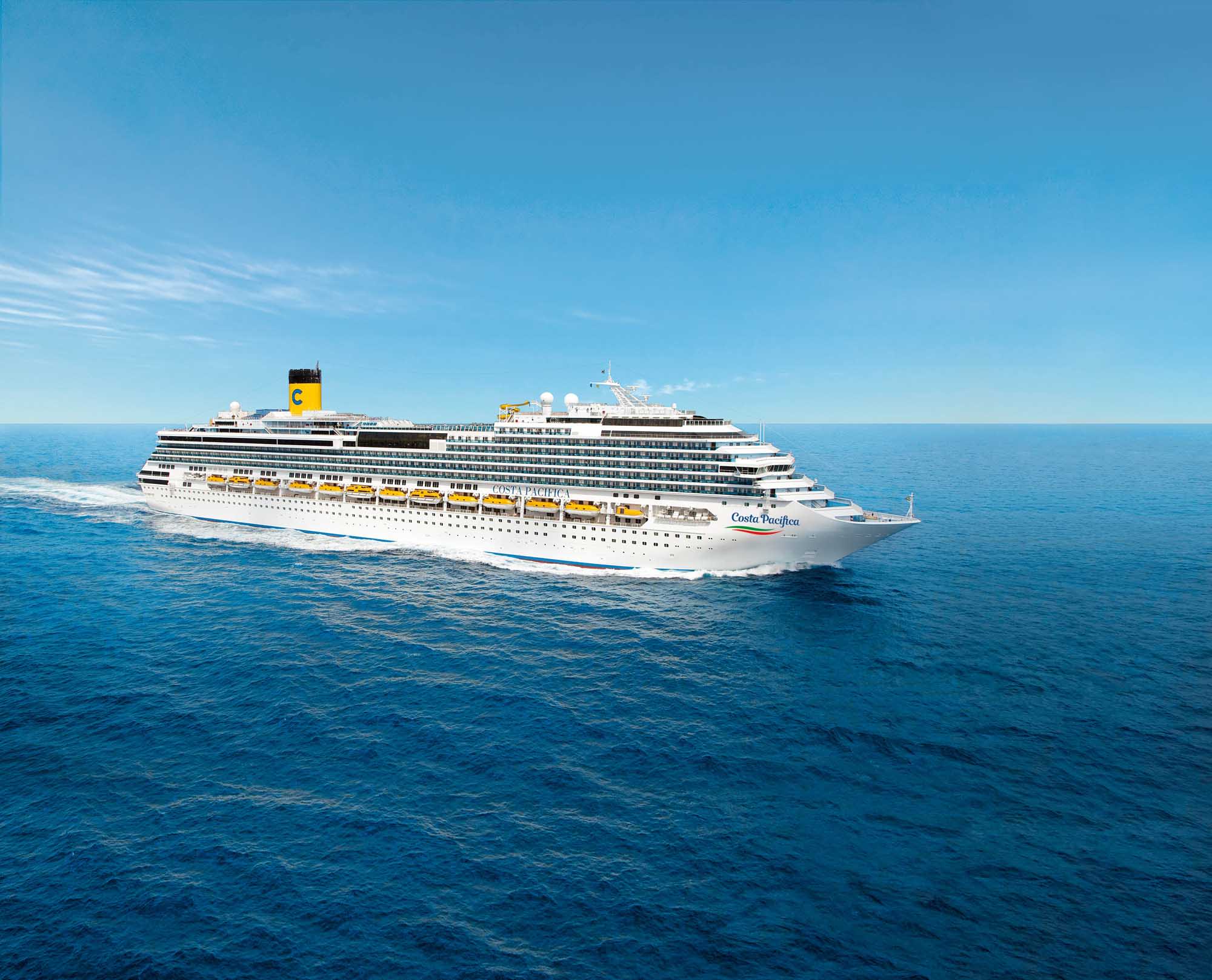 A large modern cruise ship, the Costa Pacifica, sails through calm blue waters under clear skies