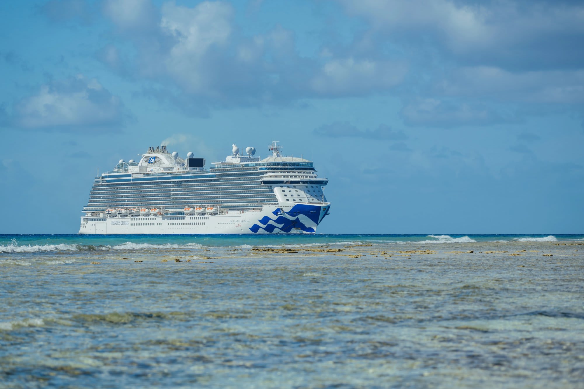 A striking full-length view of the Enchanted Princess cruise ship anchored offshore in tropical