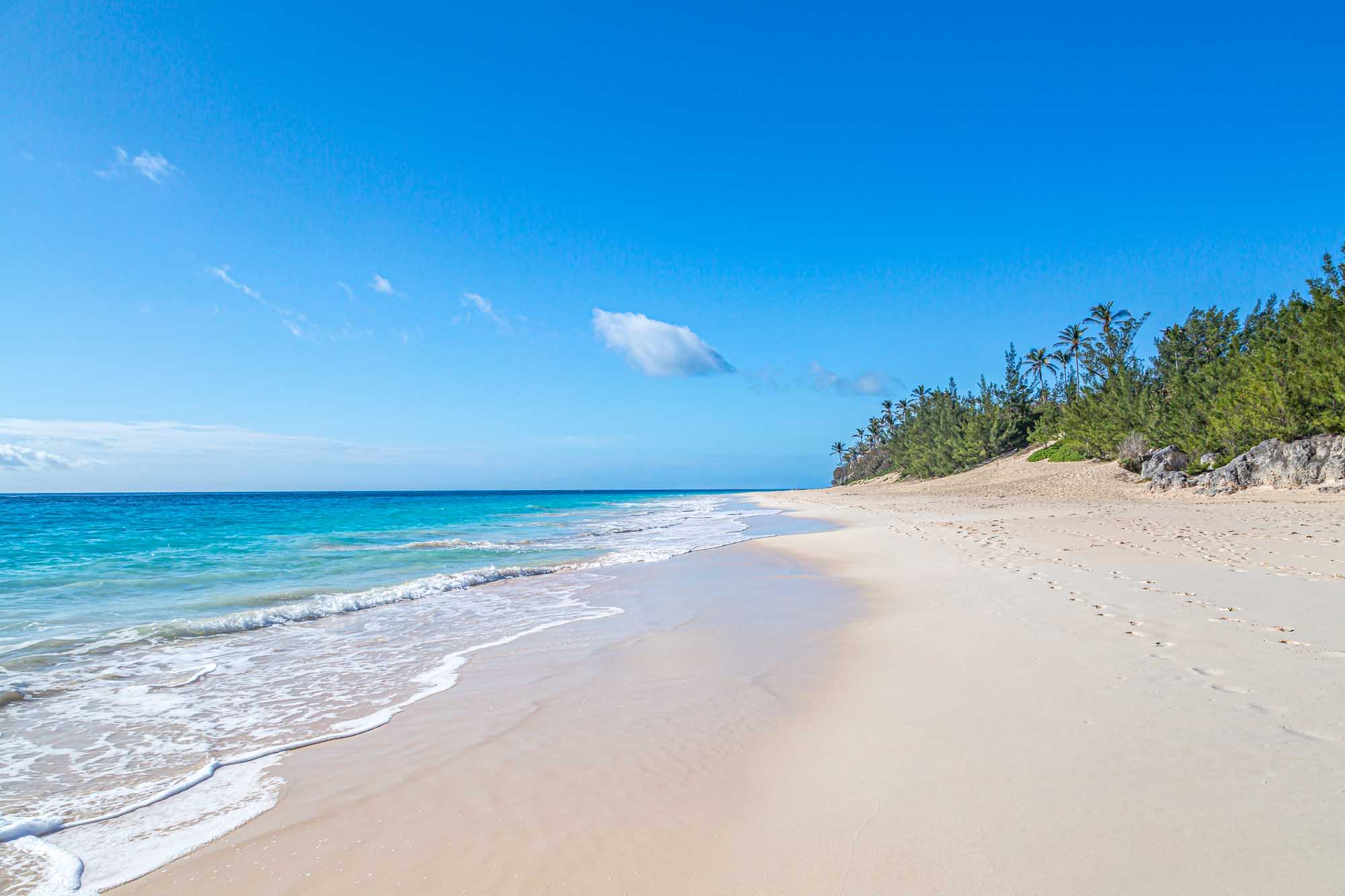 A pristine sandy beach on Bermuda's Elbow Beach stretches along crystal-clear turquoise waters