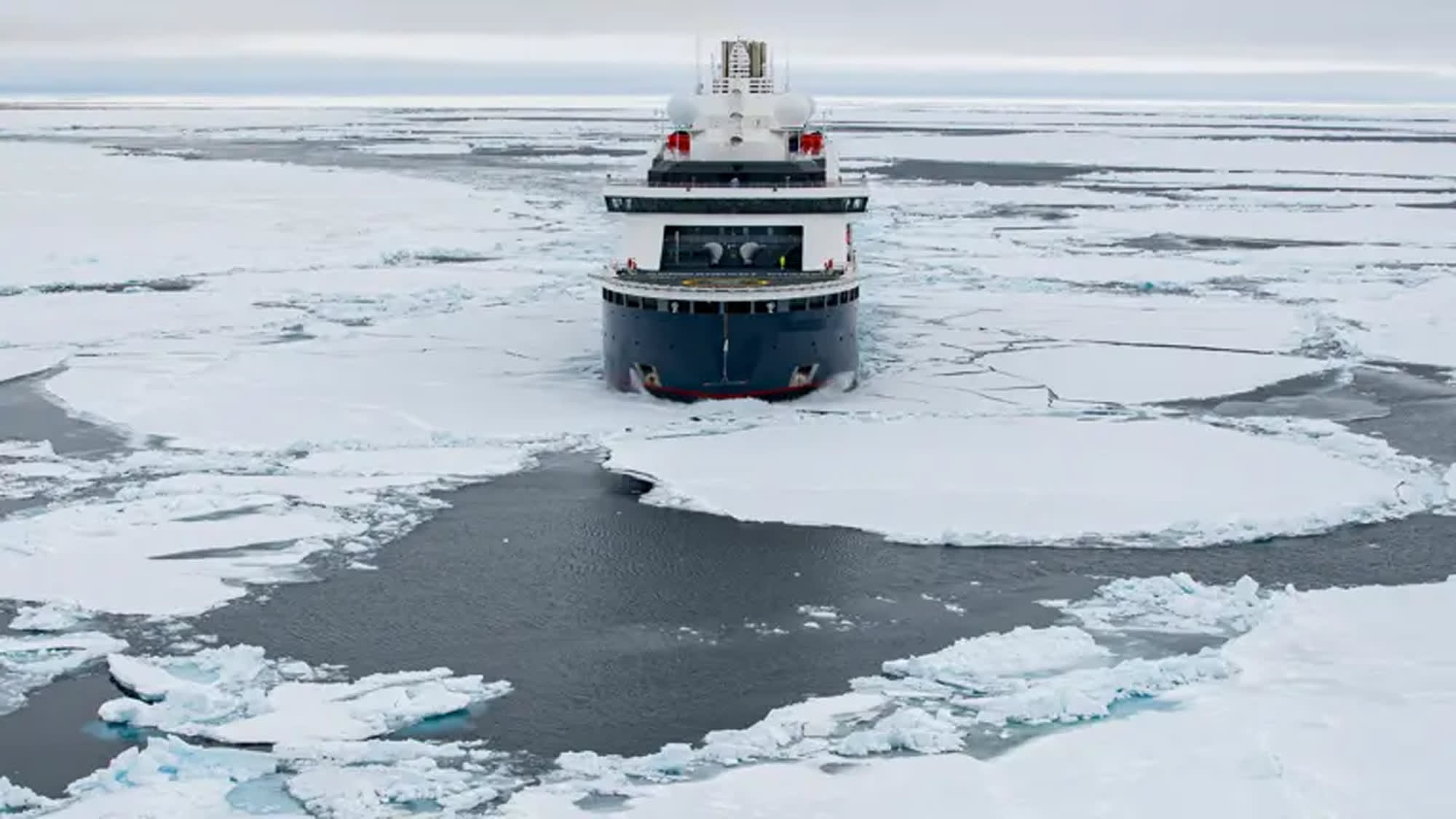 A sturdy icebreaker ship cutting through thick sea ice in a polar region, creating a distinctive
