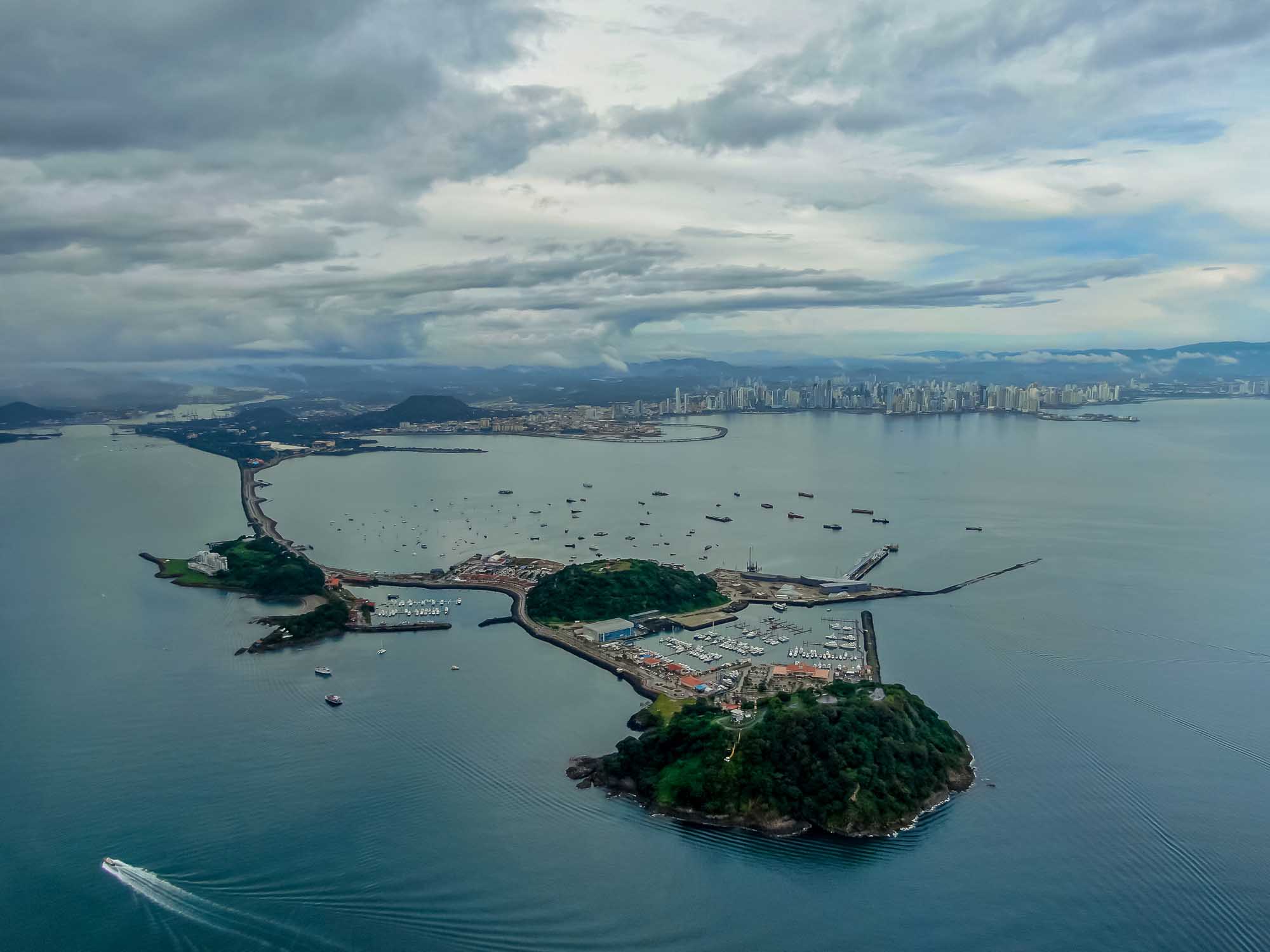 A stunning aerial photograph of Panama City's skyline across the bay, with the Amador Causeway