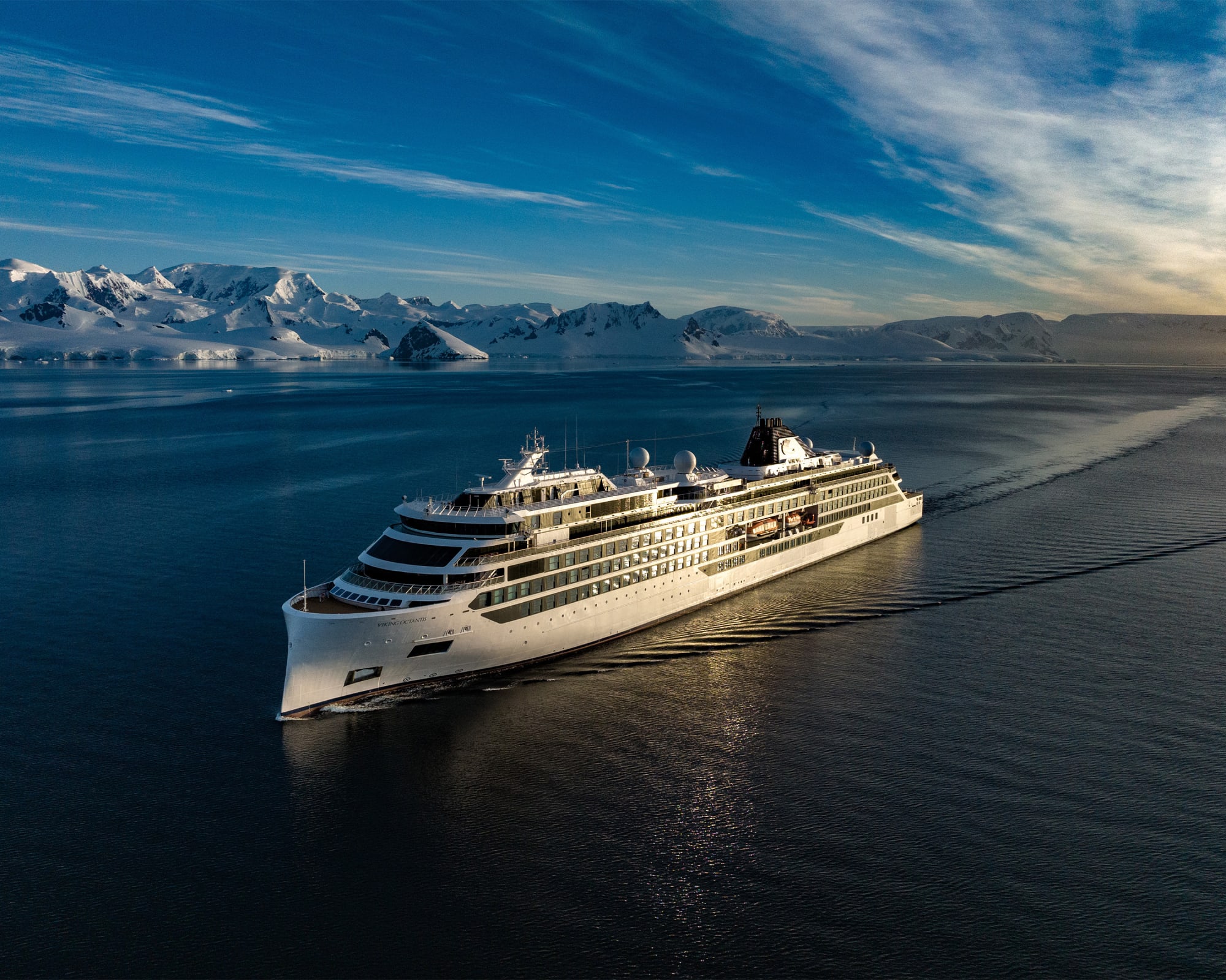 The Octantis, a luxury expedition cruise ship, navigates pristine Antarctic waters with snow-capped