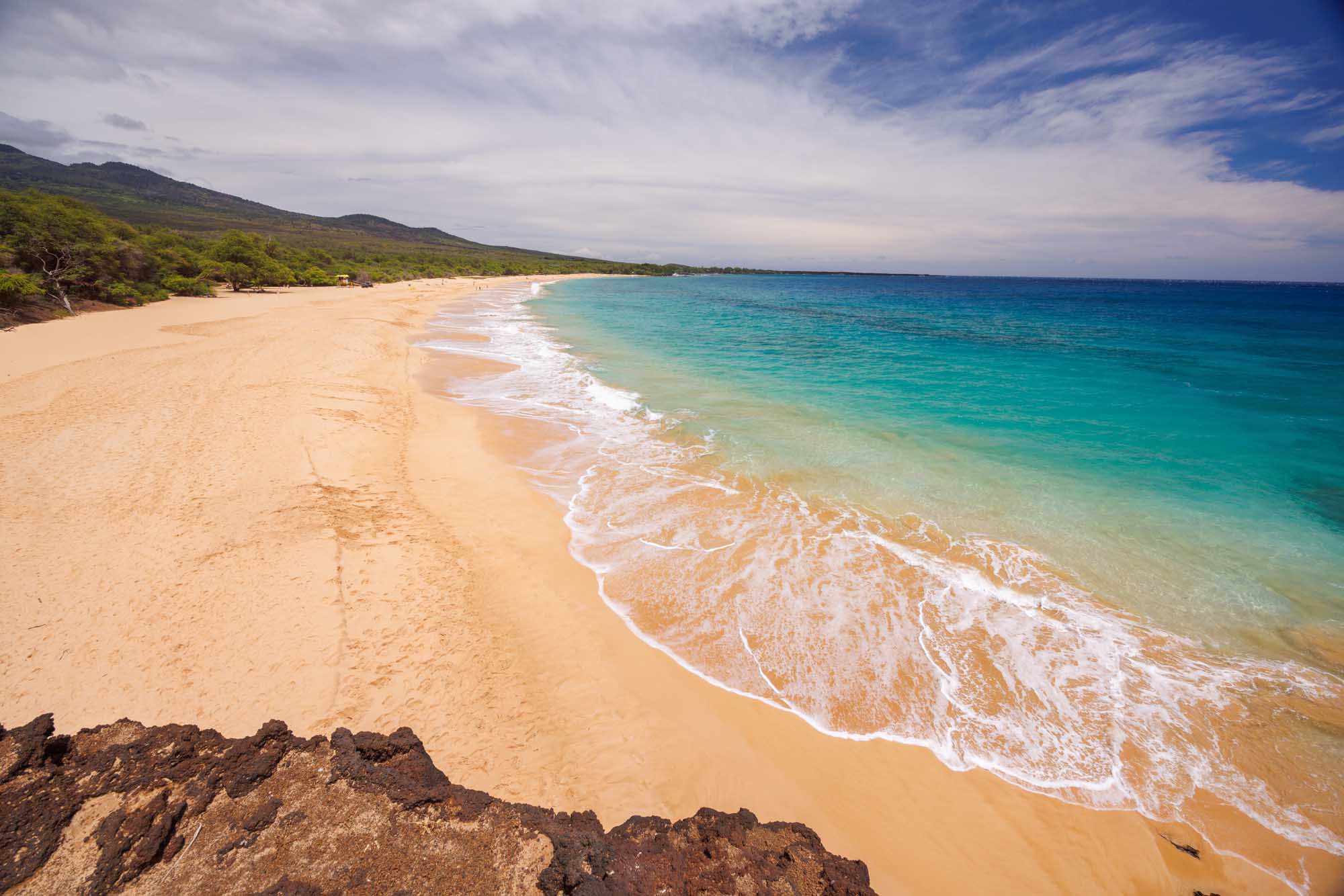 A stunning tropical beach scene in Maui, Hawaii, featuring golden sand, crystal-clear turquoise