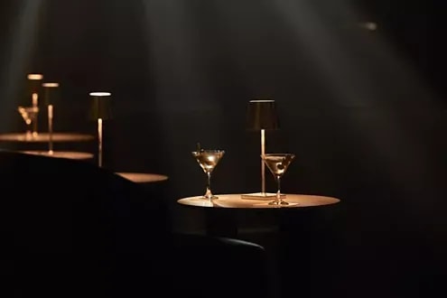 An elegant lounge aboard Explora Journeys featuring two martini glasses illuminated by warm