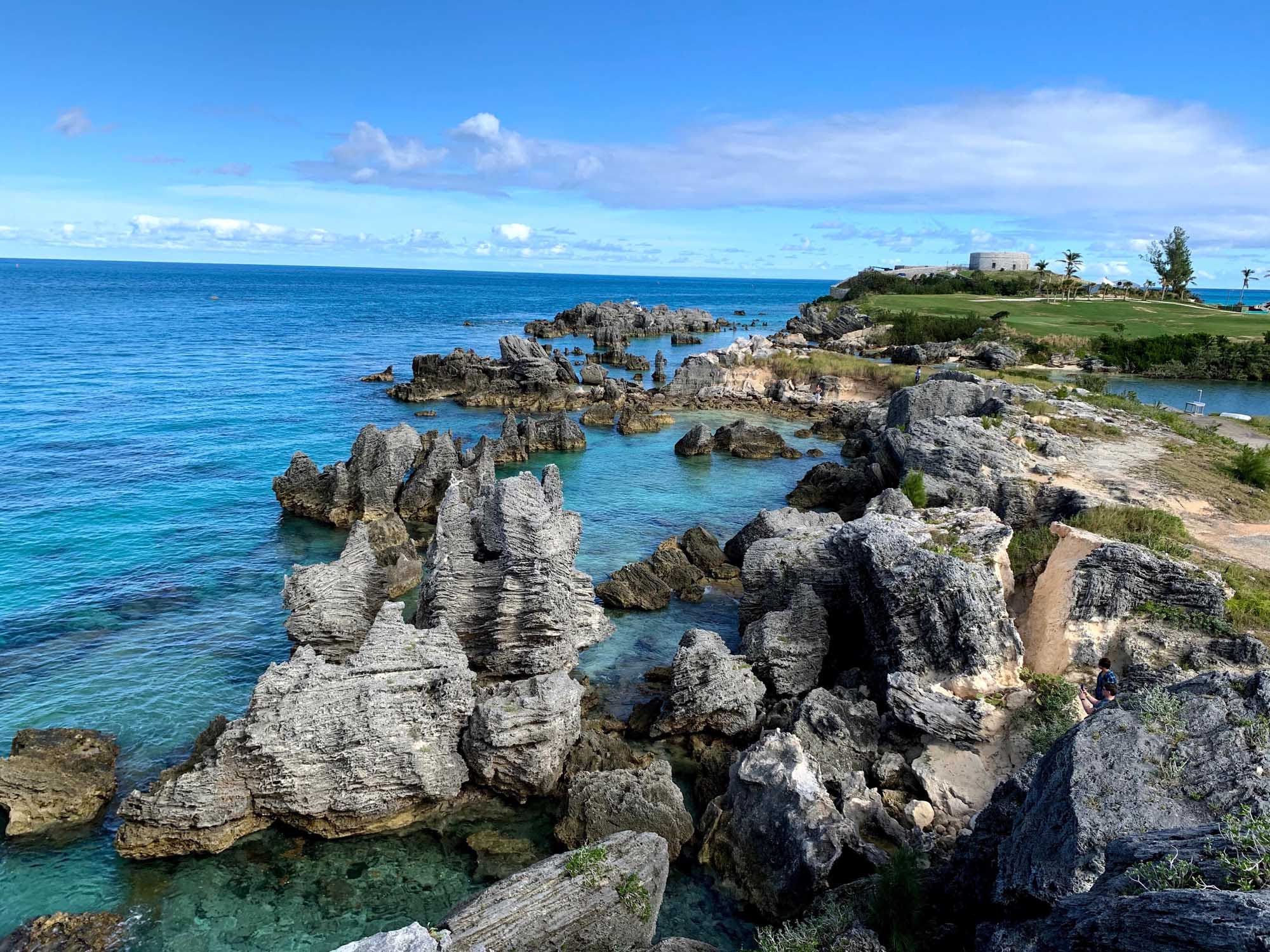 A scenic coastal landscape featuring dramatic limestone rock formations jutting into crystal-clear