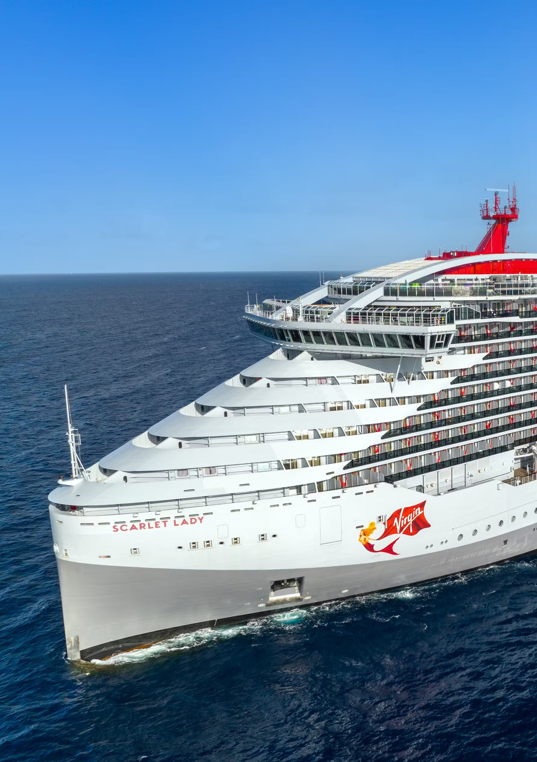 A striking aerial view of the Virgin Voyages Scarlet Lady, a modern cruise ship with distinctive