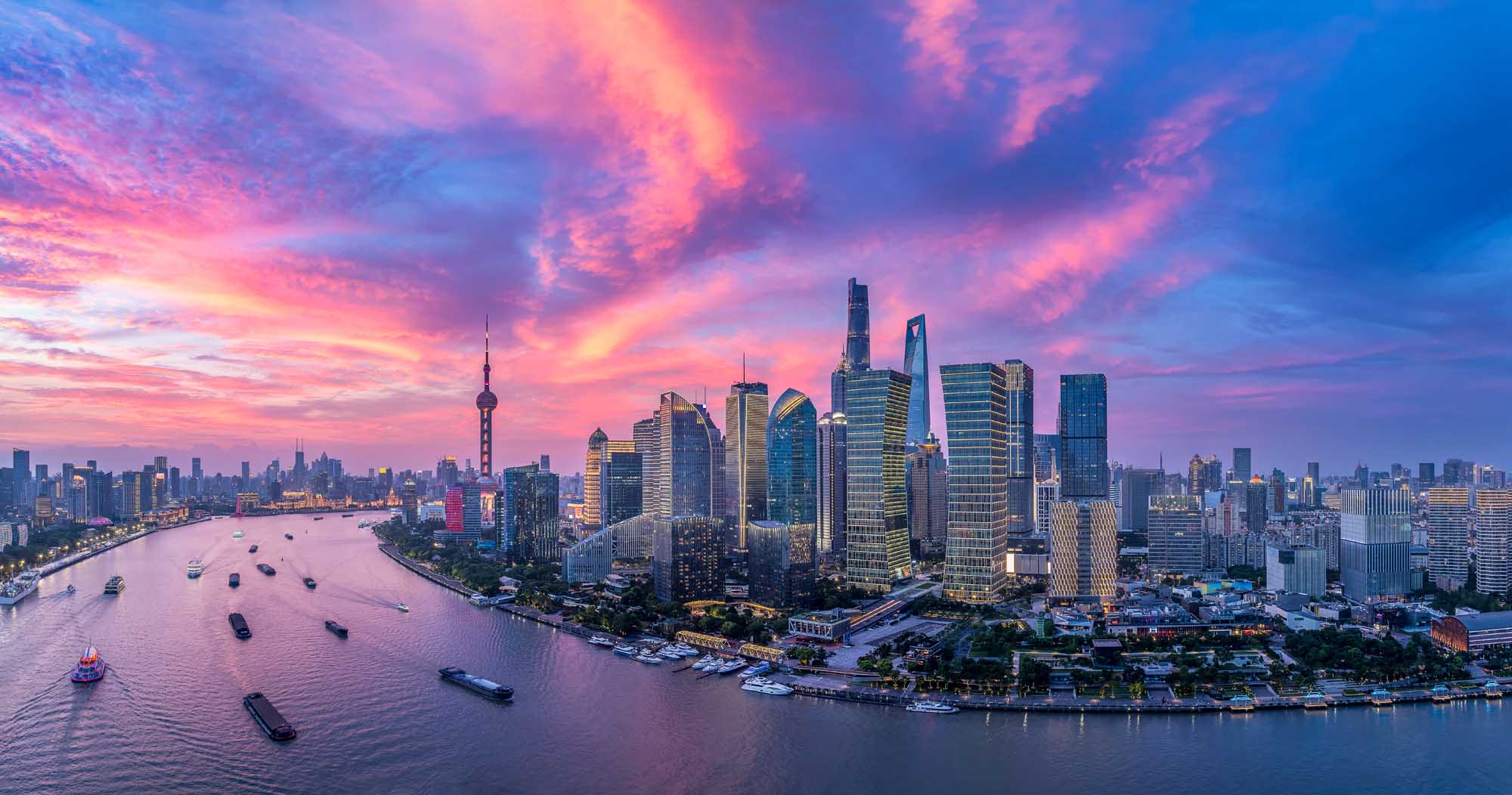 A stunning aerial view of Shanghai's iconic skyline at sunset, featuring the Oriental Pearl Tower