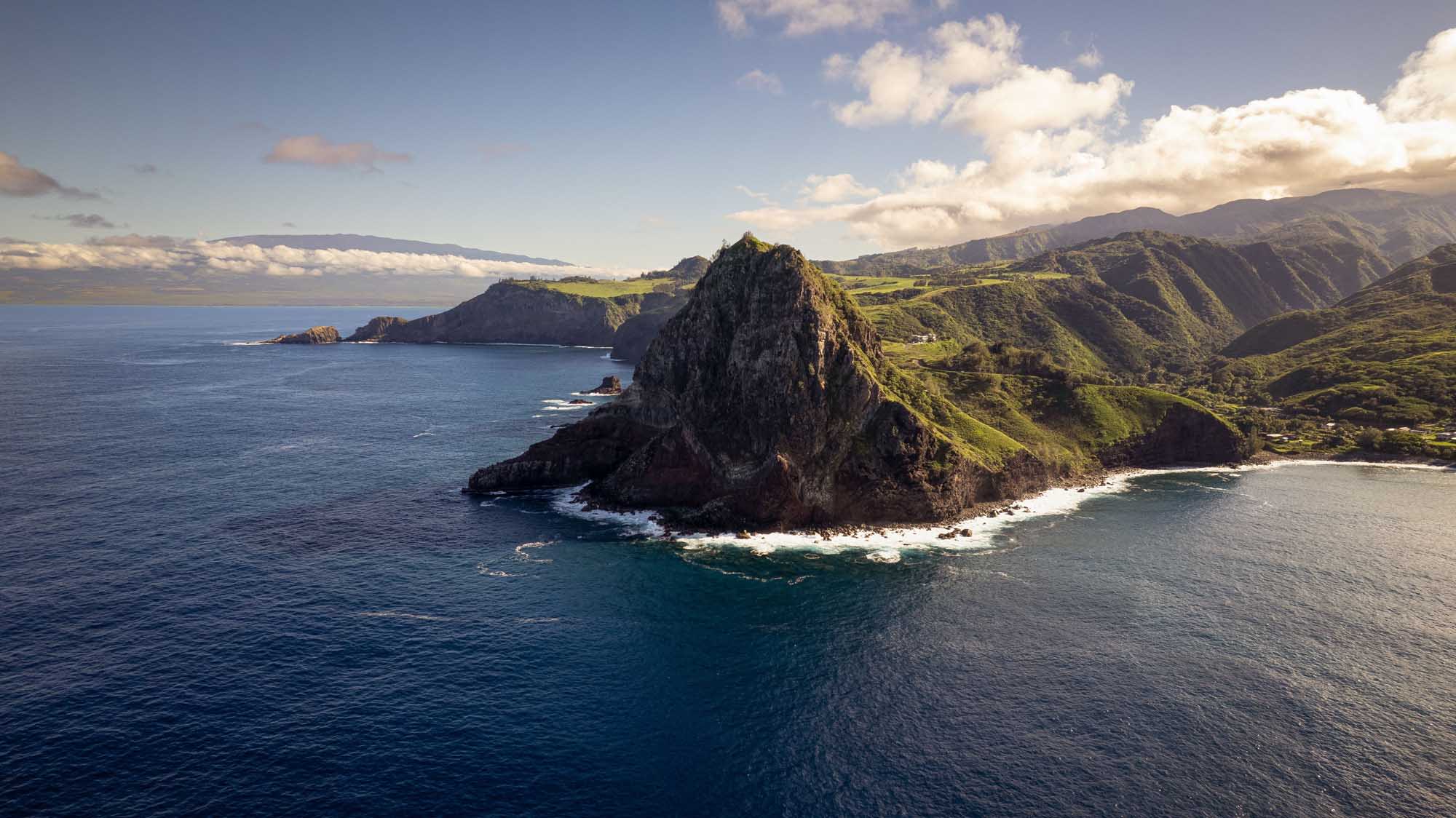 A dramatic aerial view of Kahakuloa Head, a distinctive volcanic rock formation jutting into