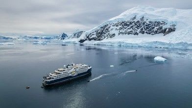 A sleek expedition cruise ship navigating through remote polar waters, showcasing the purpose-built design and ice-class capabilities typical of Swan Hellenic's fleet.