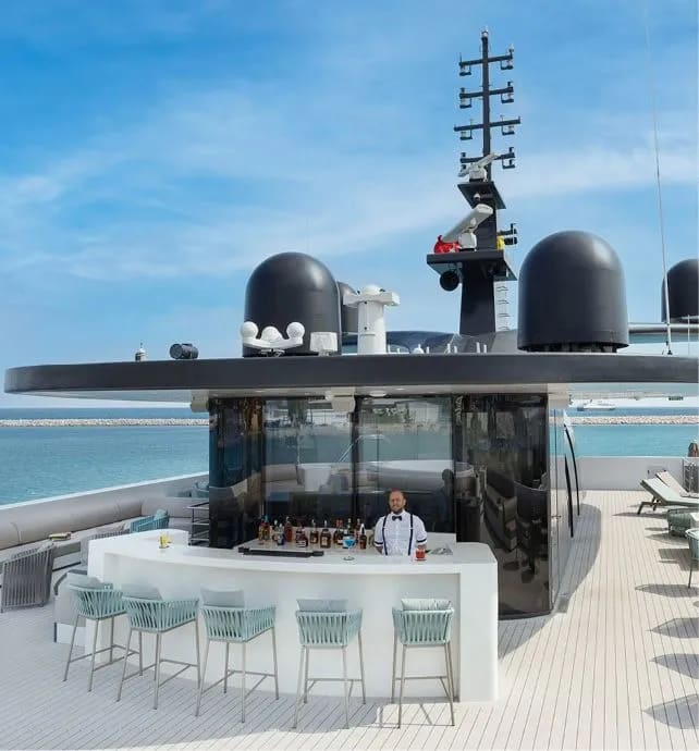 An elegant outdoor bar and lounge area on the sky deck of a luxury expedition yacht, featuring