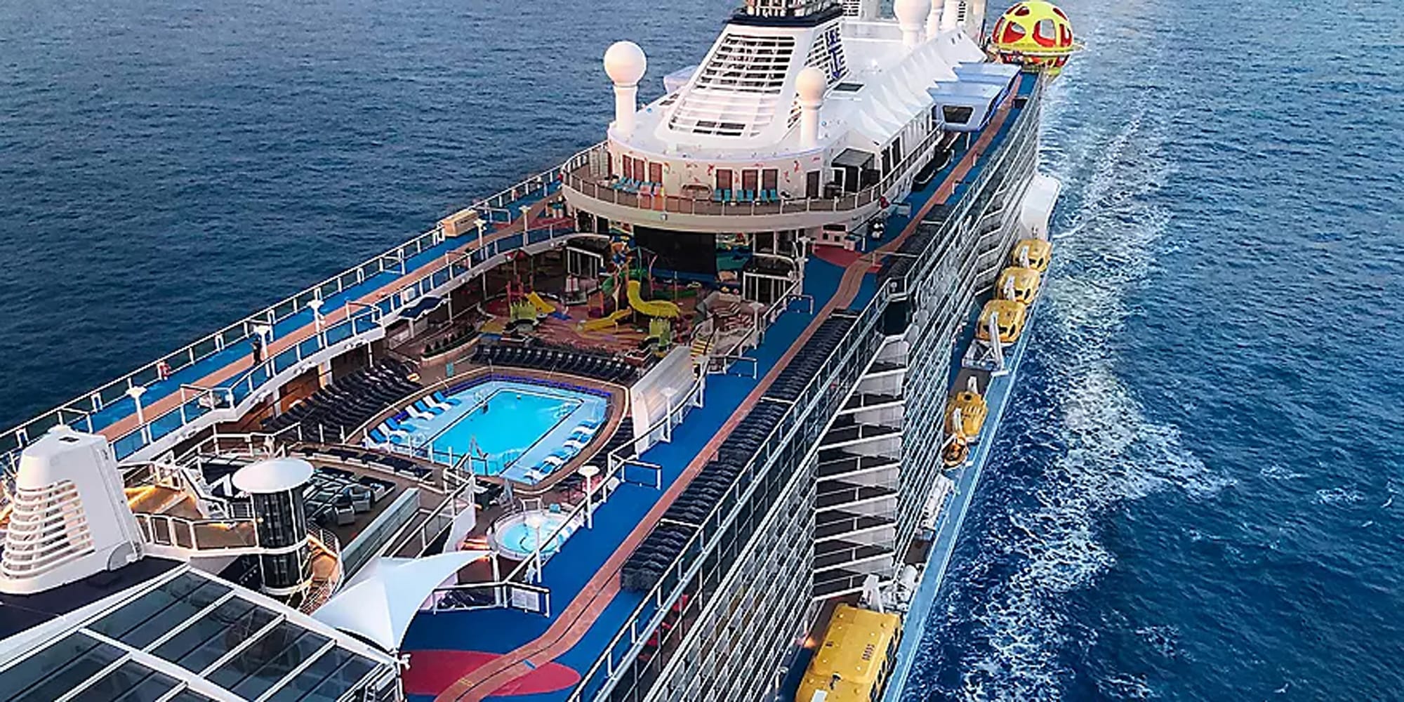 An aerial view of a modern cruise ship showcasing multiple deck levels with a bright blue swimming
