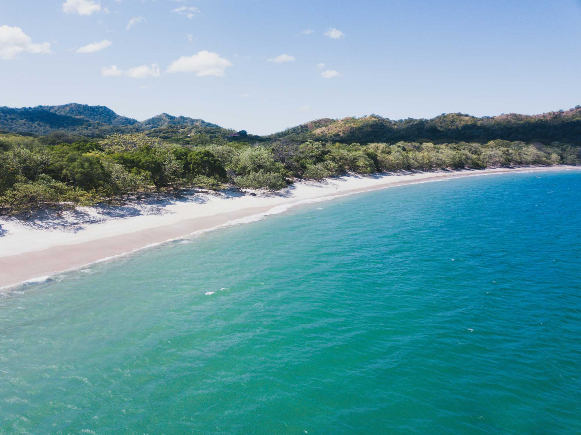 A stunning aerial view of a secluded tropical beach featuring pristine white sand, crystal-clear