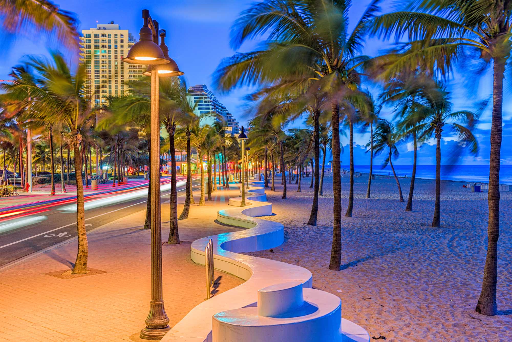 A scenic twilight view of Fort Lauderdale's beachfront promenade featuring illuminated street
