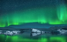 A stunning display of vibrant green aurora borealis dancing across the night sky above a glacial