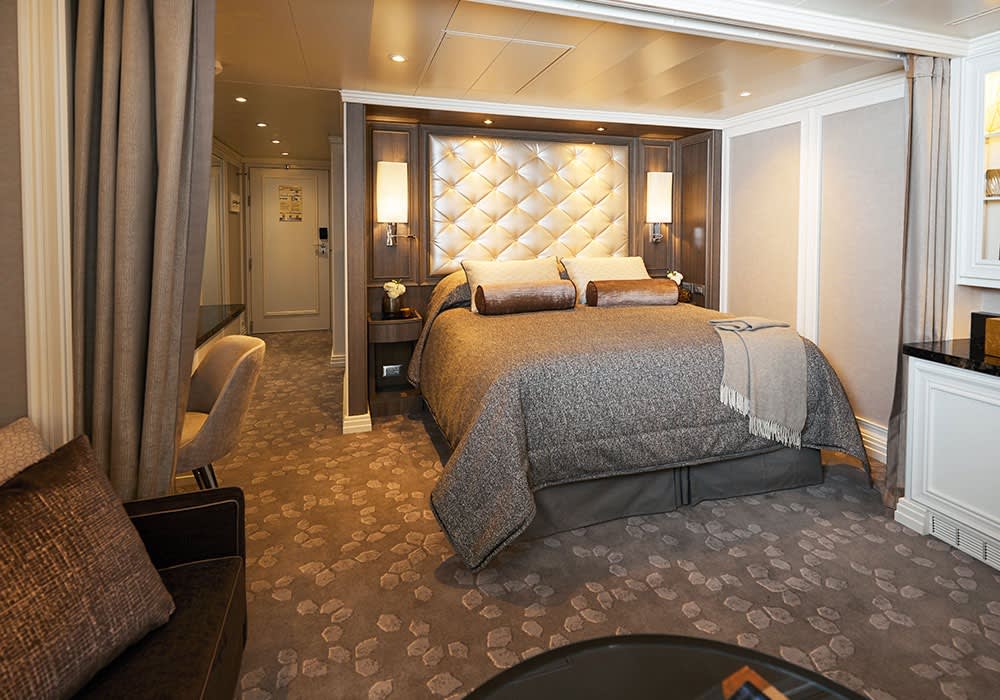 A luxurious suite bedroom aboard Regent Seven Seas Cruises, featuring an elegantly appointed space