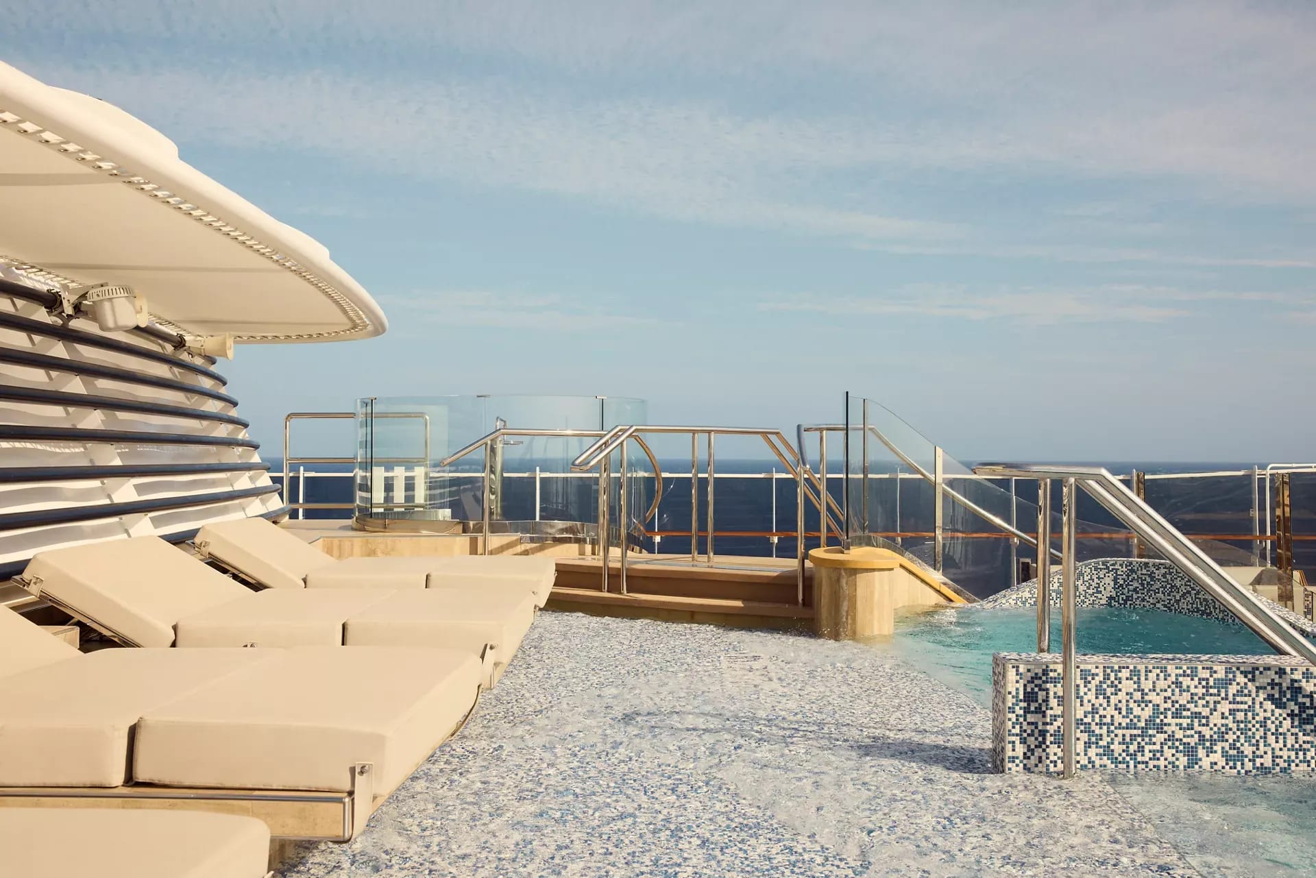A luxurious pool deck aboard the Explora Journeys Helios featuring loungers, a swimming pool