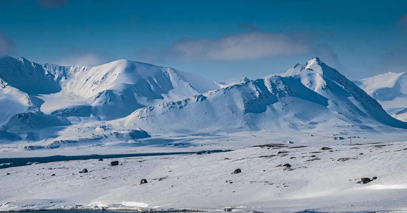 A pristine Arctic landscape featuring majestic snow-capped mountains and a frozen valley with
