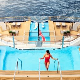 An overhead view of an elegant swimming pool aboard a luxury yacht, featuring a solitary guest