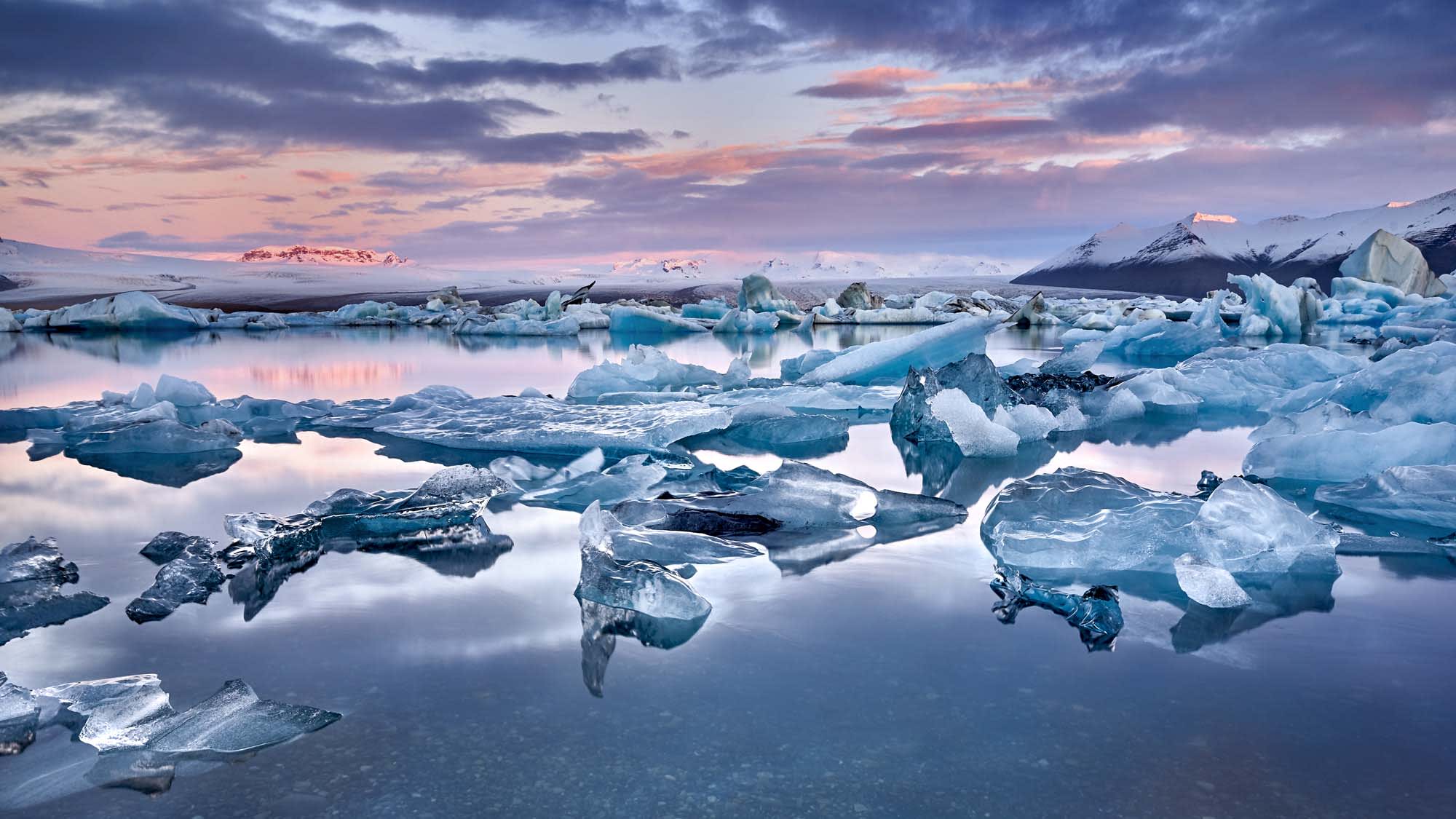 A breathtaking panoramic view of Iceland's Jökulsárlón glacier lagoon at twilight, featuring