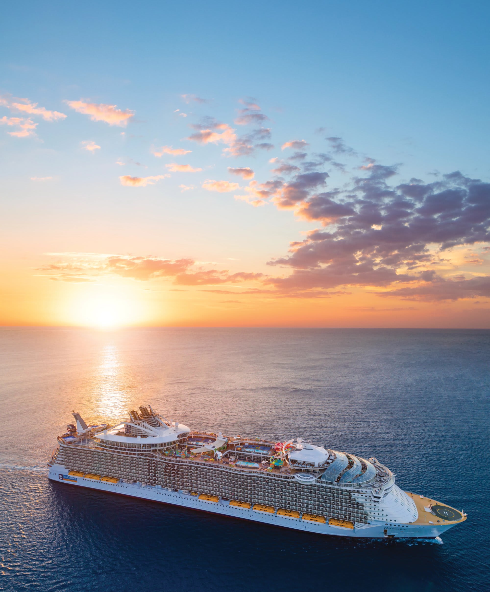 A magnificent large cruise ship sails through calm blue waters during a stunning golden hour