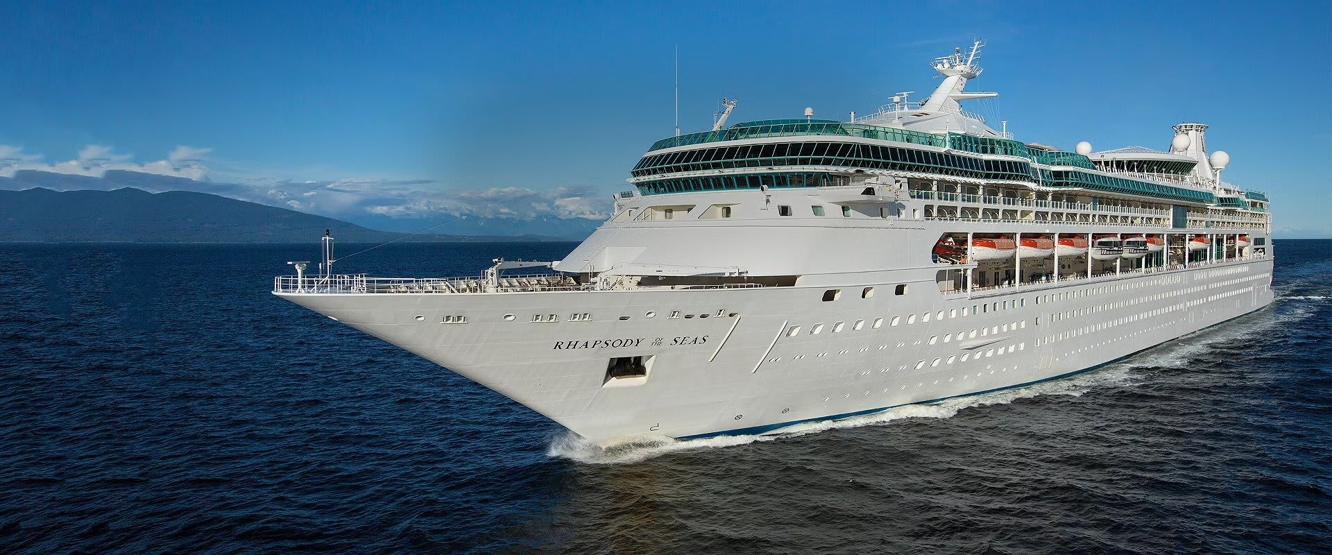 A magnificent large cruise ship, the Rhapsody of the Seas, sails through deep blue waters