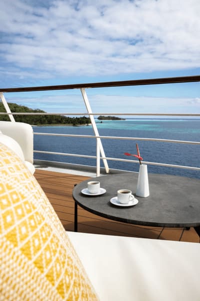 An elegant balcony cabin aboard a luxury cruise ship featuring a yellow geometric patterned