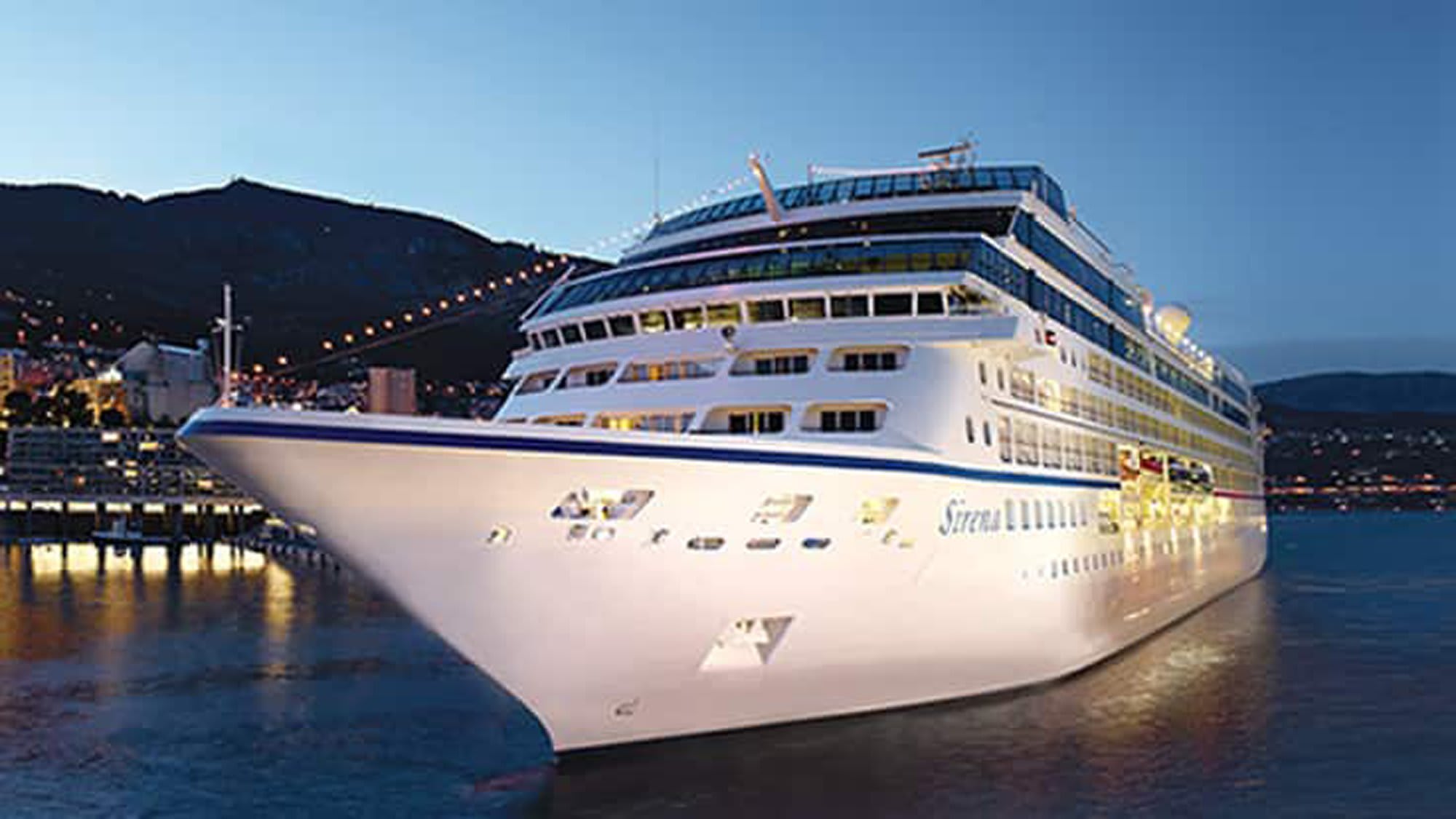 A luxurious white and blue cruise ship docked at a port in Monte Carlo during twilight