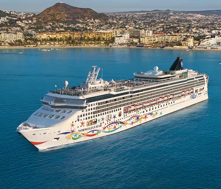 A large modern cruise ship, the Norwegian Star, anchors in brilliant turquoise Mediterranean waters