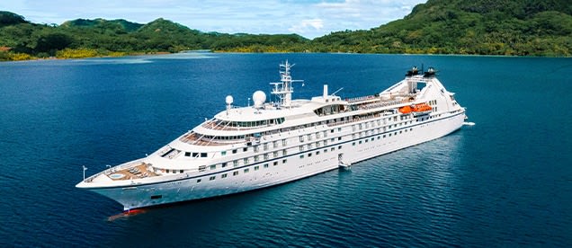 A sleek all-white luxury cruise yacht, the Star Breeze, anchored in clear turquoise waters