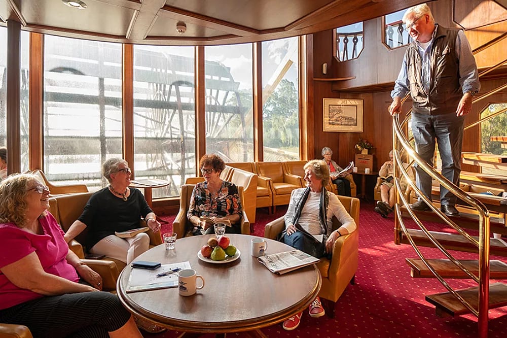 An elegant lounge area aboard a river cruise ship featuring large curved windows with panoramic